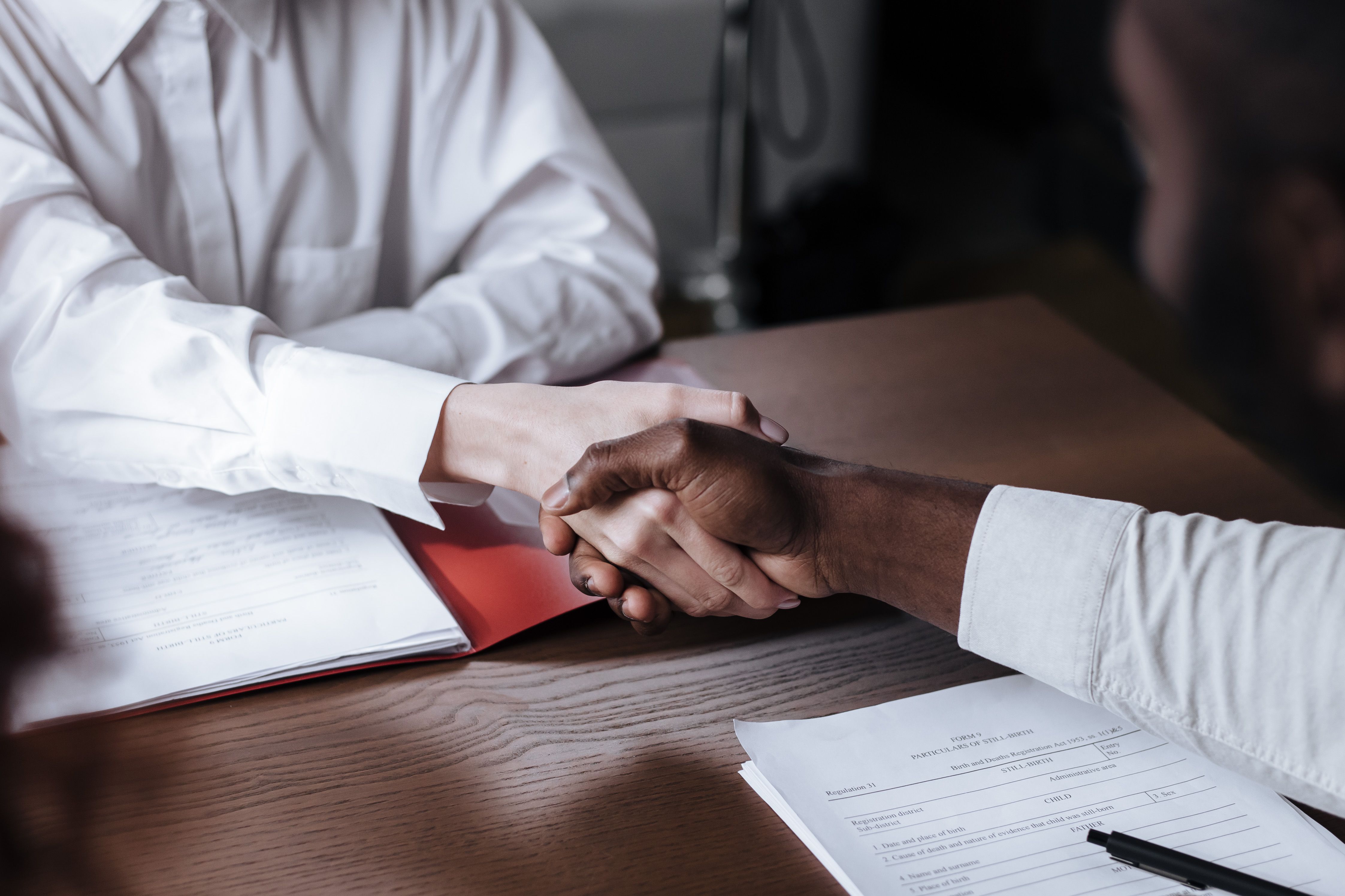 Business handshake over legal documents representing liability agreements between employer and employee