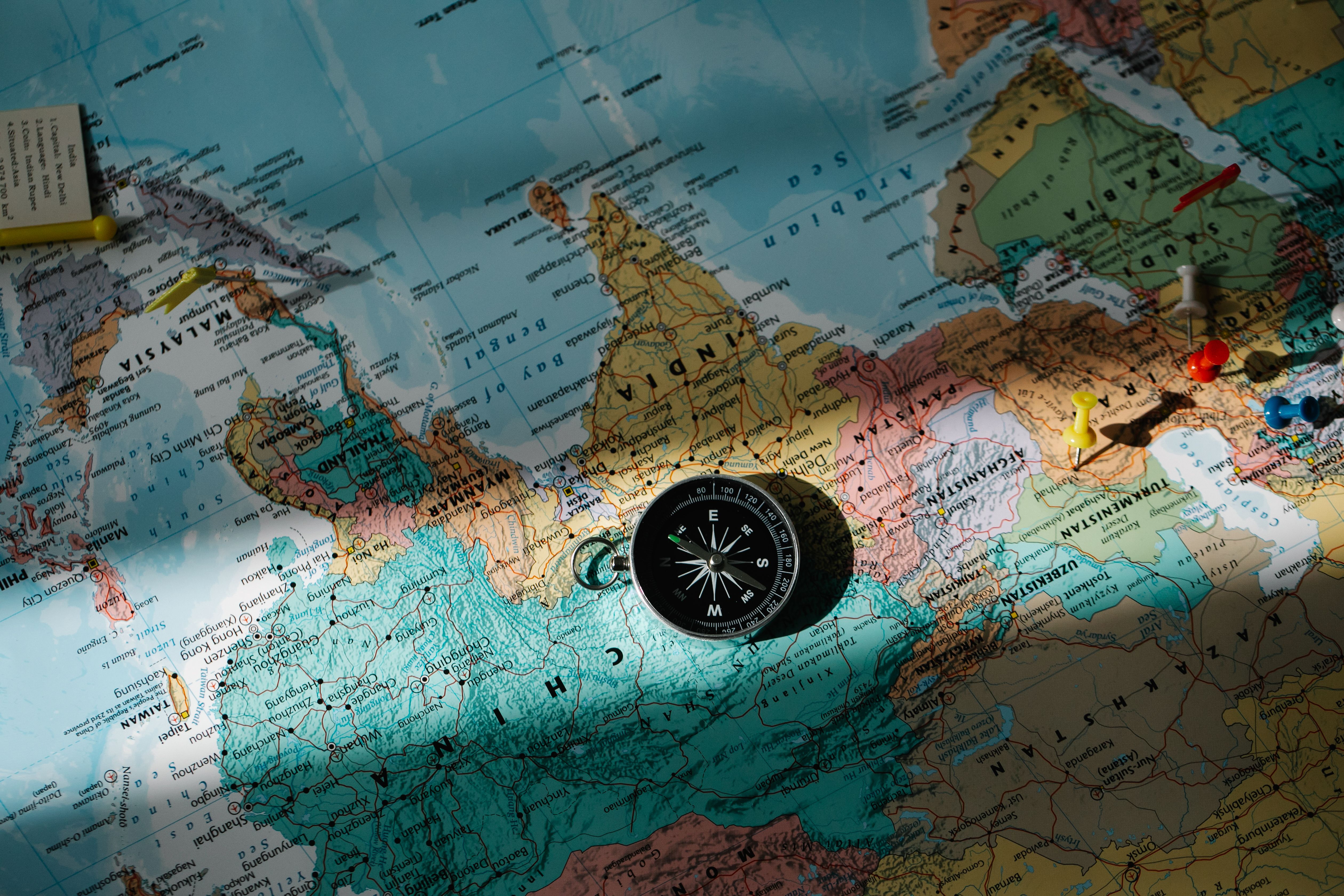 Compass on a world map with push pins marking destination countries