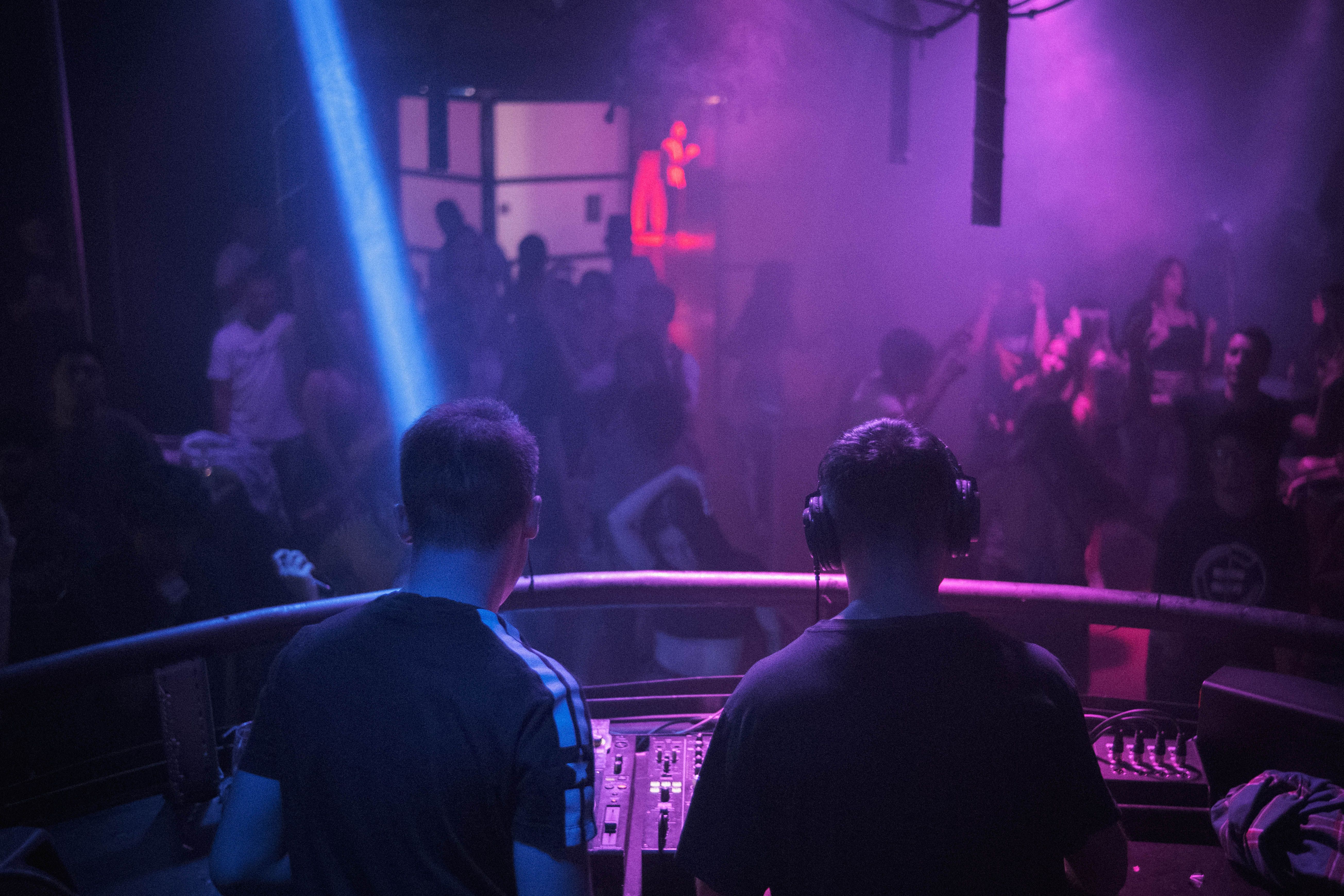 DJ performs for a dancing crowd under vibrant lights in an exclusive nightclub atmosphere.