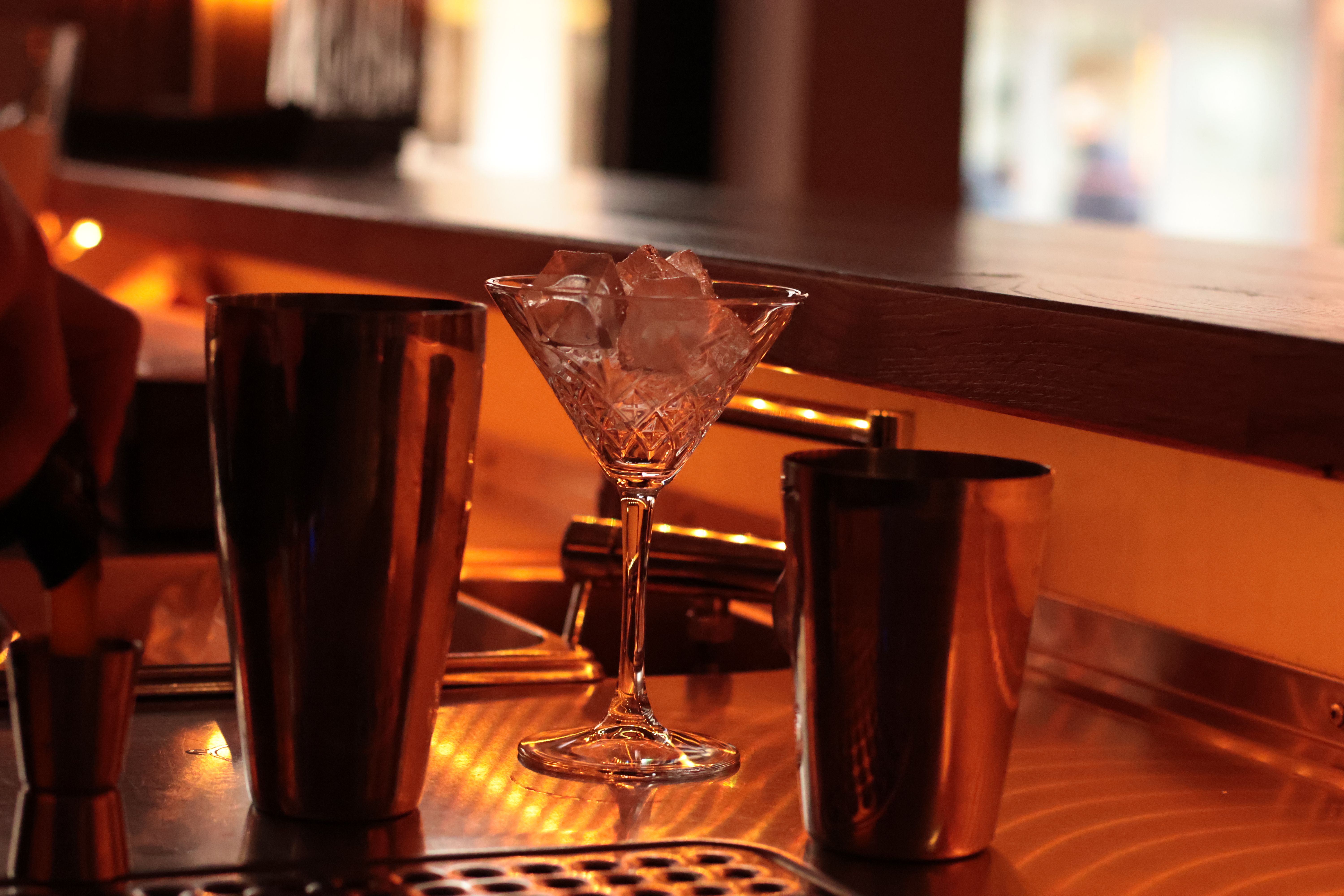 Martini and cocktail tools on an elegant bar counter in a warm, upscale lounge.